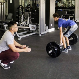 Certified Personal Trainer, Vincet, observes Tanner perform a deadlift.
